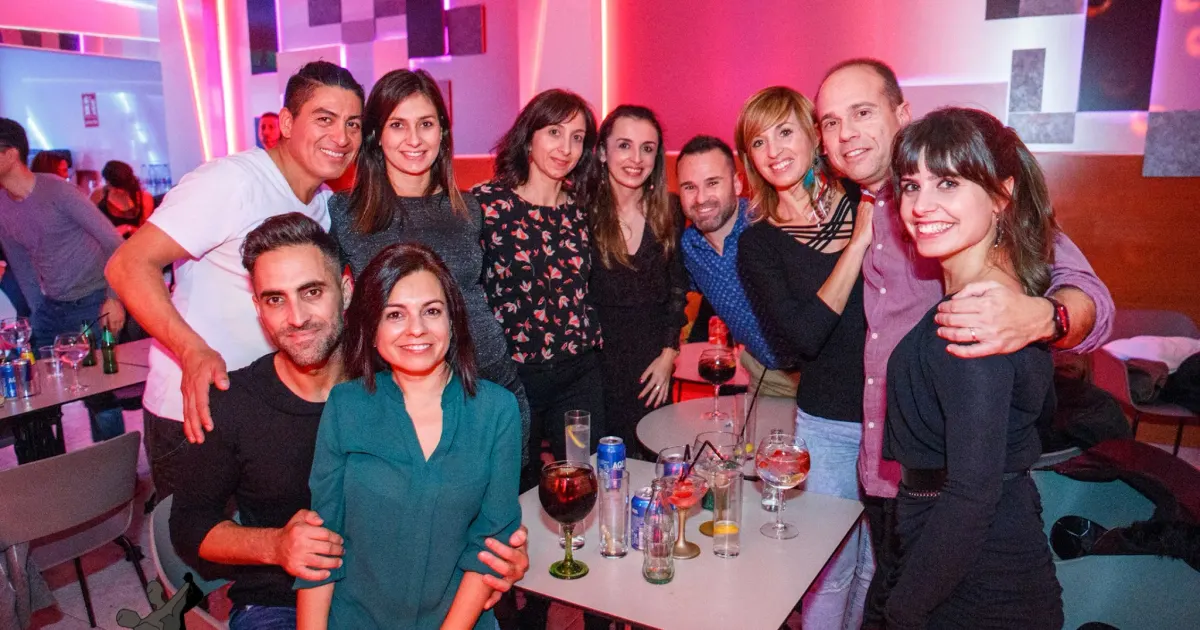 Grupo de asistentes en la zona de mesas y barra de la sala